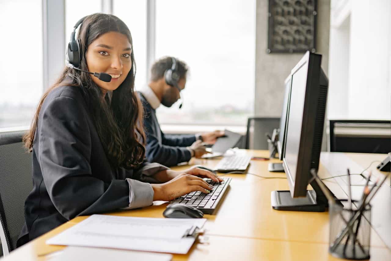 Operatori di call center con cuffie e microfono al lavoro in un ufficio moderno, concentrati sul servizio clienti e sull'assistenza telefonica.