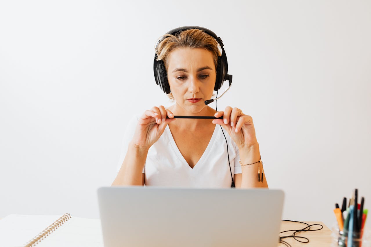 Operatrice di call center con cuffie e microfono mentre lavora da remoto al computer portatile – software per contact center moderno e gestione professionale delle chiamate.