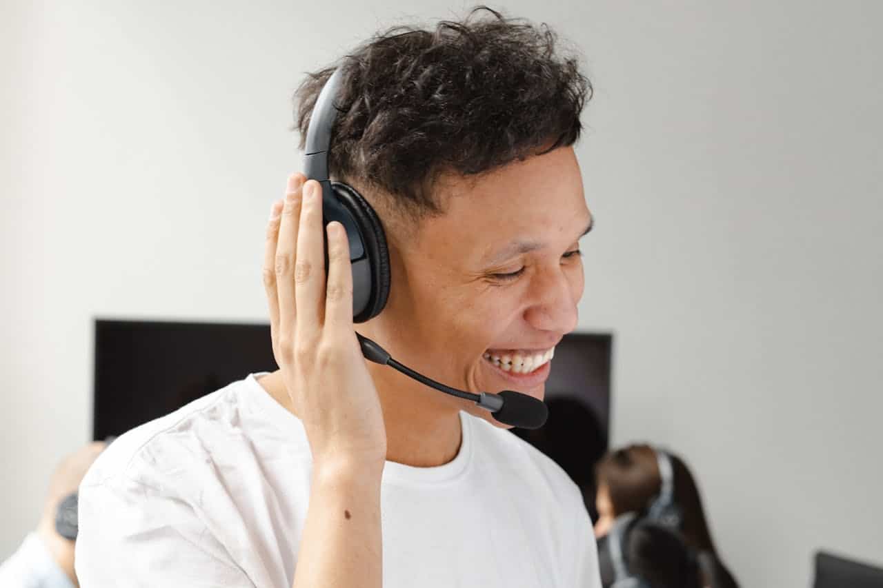 Operatore call center sorridente con cuffie e microfono, durante una chiamata outbound